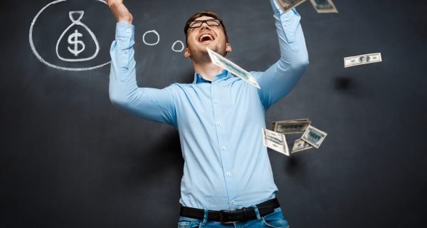 handsome man standing over blackboard. Holding and throwing dollars in his hands and smiling.